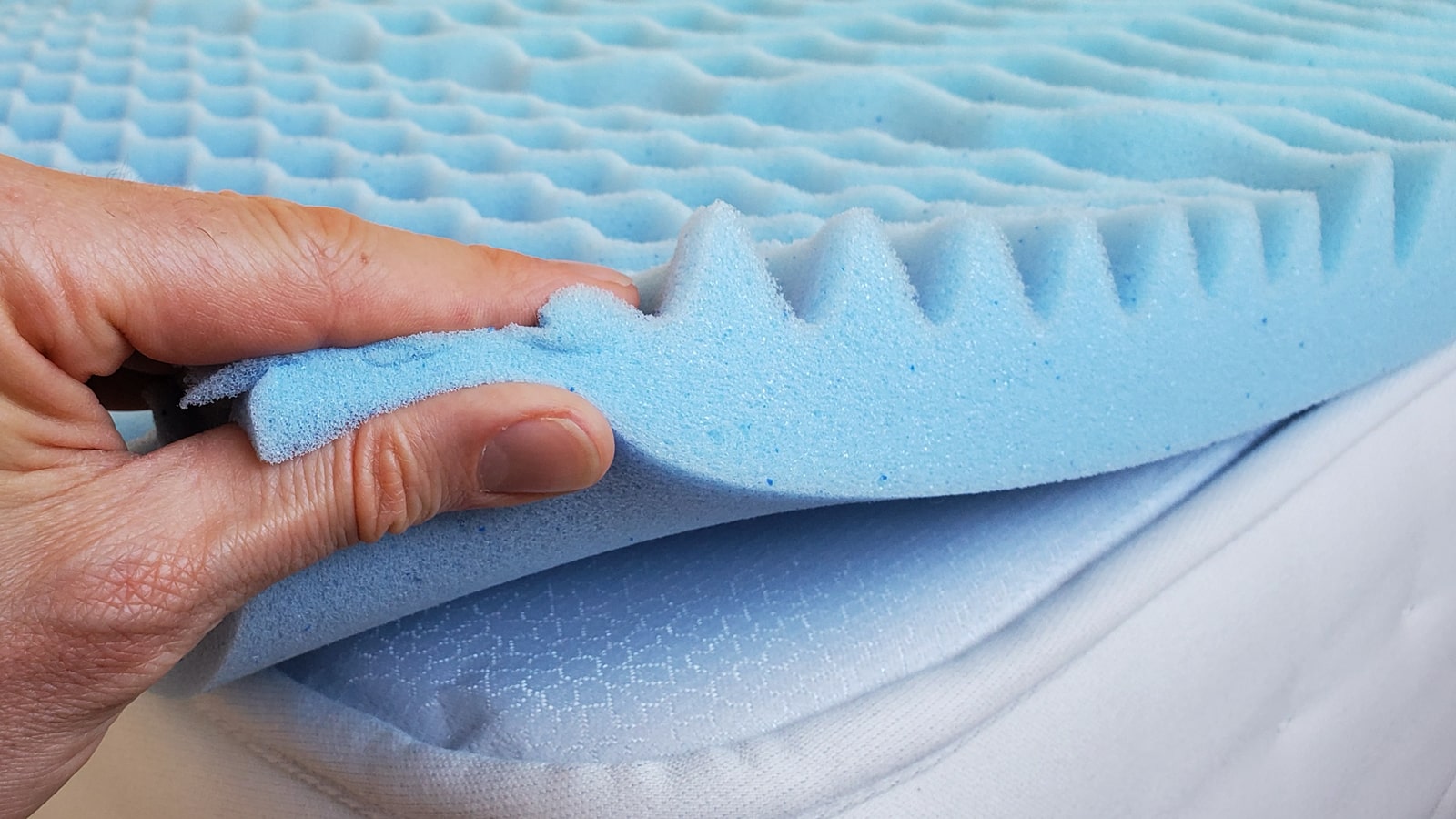 hand squeezing a memory foam topper