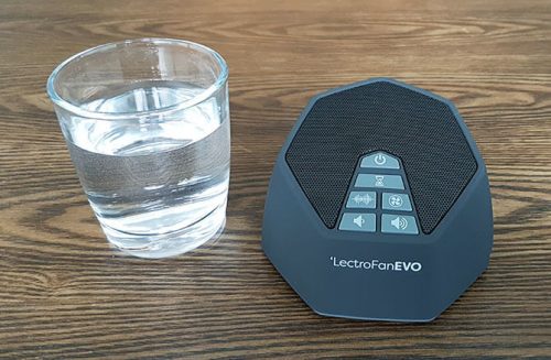 lectrofan evo white noise machine next to a small glass of water showing it is a compact size