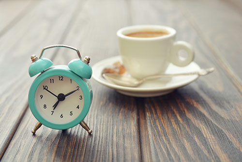 photo of an alarm clock and cup of coffee