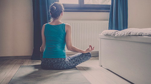 photo of a woman doing a yoga meditation in her bedroom