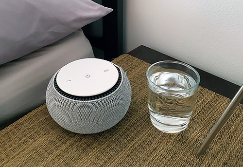 photo showing the SNOOZ on a nightstand next to a glass of water to compare the size