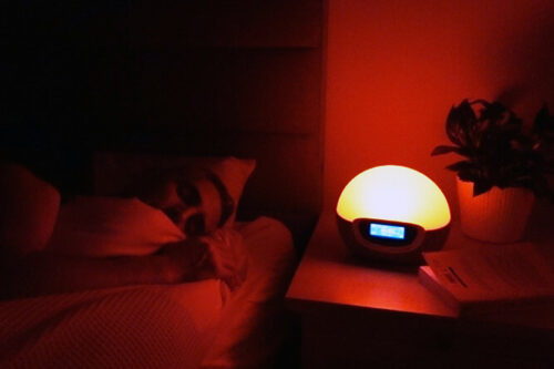 man sleeping while the lumie bodyclock shine 300 is on a red nightlight setting