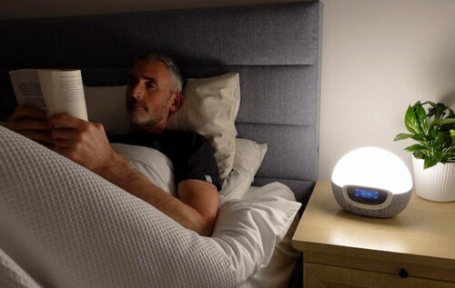 photo of the author ethan green reading in bed with the lumie bodyclock nightlight function