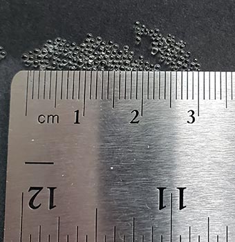 glass microbeads from a weighted blanket next to a ruler to show they are around 1mm in diameter