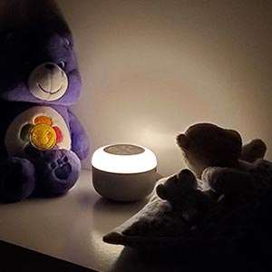 yogasleep travel mini with the nightlight on in a bedroom