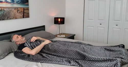 man sleeping under the Weighted Evolution blanket in a bedroom
