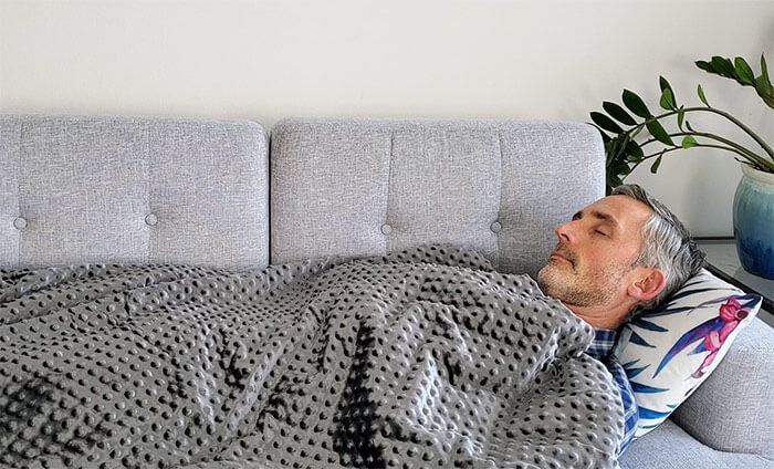 A man sleeping under a weighted blanket covered in sensory nodes