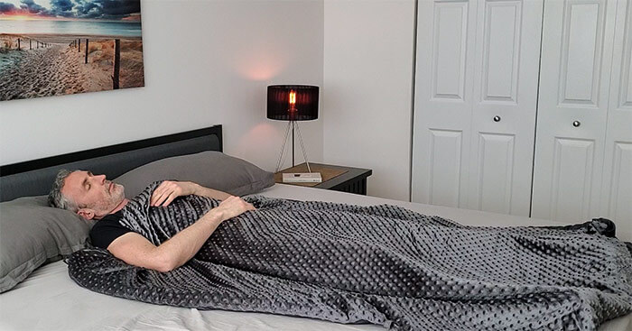 man sleeping under the Weighted Evolution blanket in a bedroom