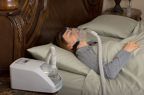woman sleeping while connected to a cpap machine
