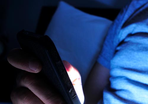 person using a smartphone in the dark in bed