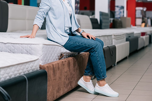 woman sitting on a mattress in a mattress store