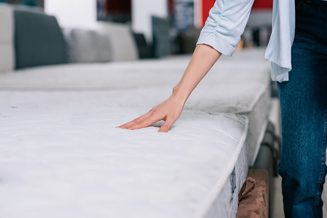 photo of a woman testing a mattress topper in a shop
