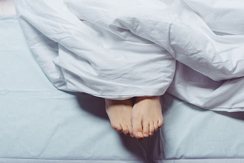 photo of feet poking out from under a duvet