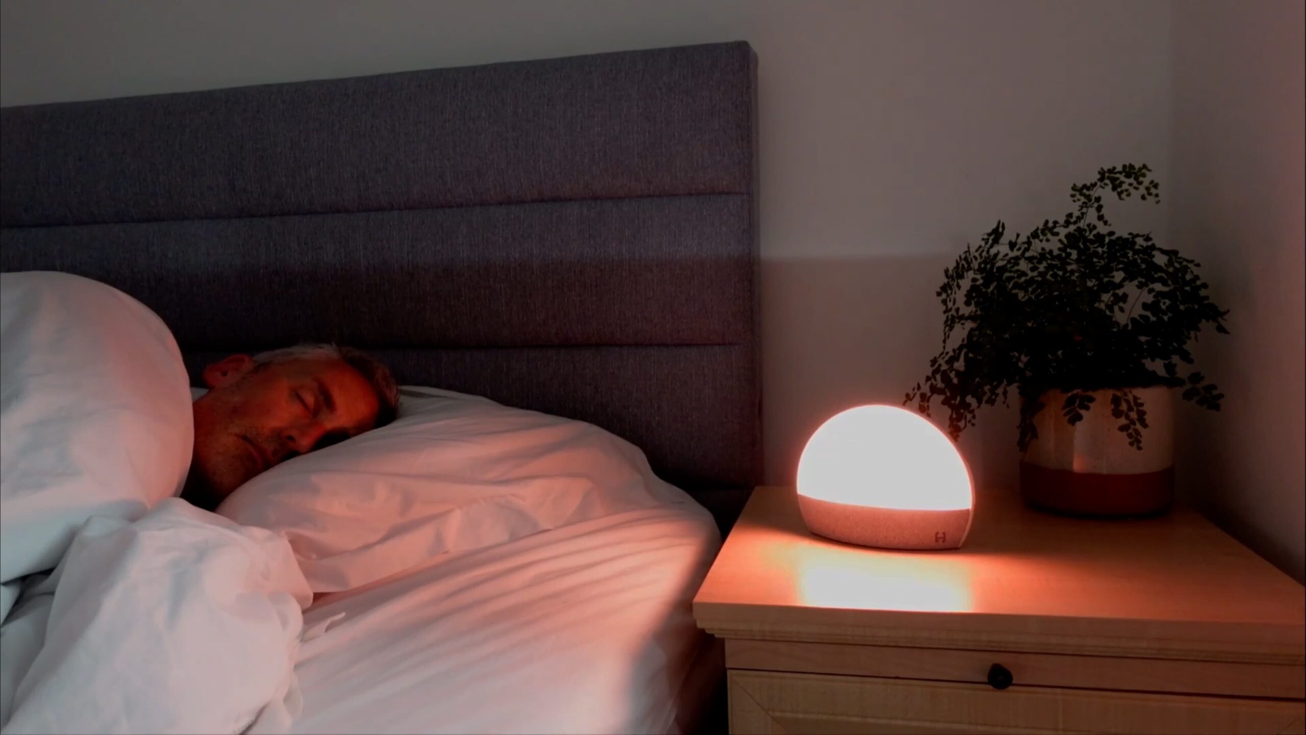 man sleeping with the hatch restore glowing with an orange color on a nightstand