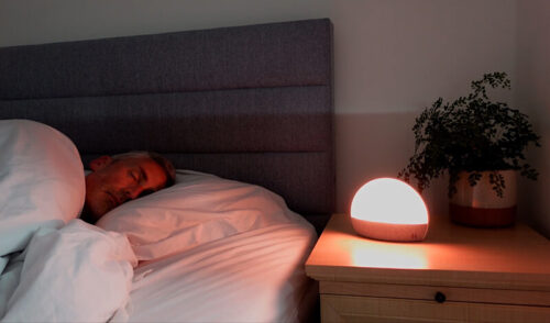 man sleeping with the Hatch Restore wake up light in sunrise mode