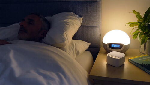 man sleeping with the magicteam white noise machine on a nightstand