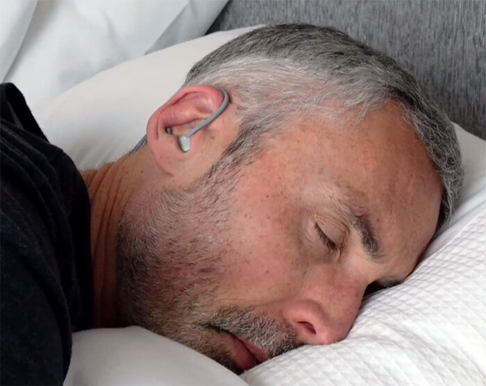 photo of a man wearing the Kokoon Nightbuds headphones while sleeping in bed