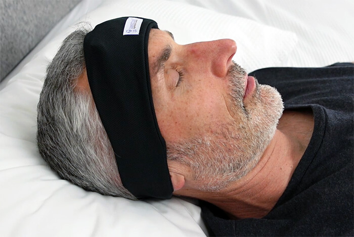 photo of a man sleeping in bed wearing the SleepPhones headphones