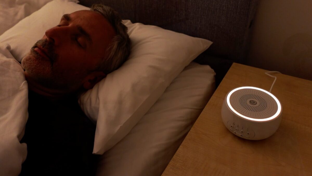 man sleeping with the Yogasleep Dreamcenter on the nightstand