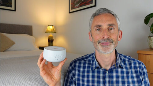 man holding Yogasleep Dreamcenter in a bedroom