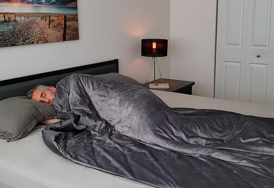 man in bed using the luxome weighted blanket