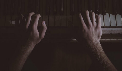 hands playing the piano in the night