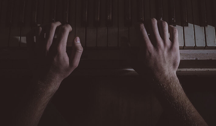 hands playing a piano in the night