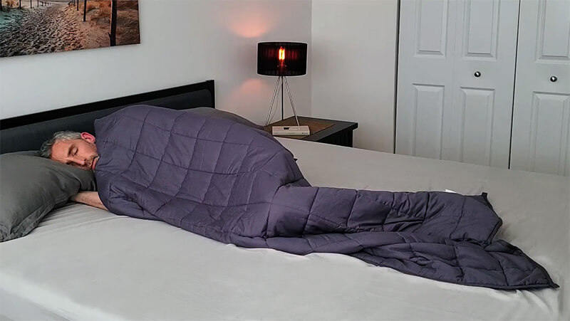 A man lying in bed under the YNM weighted blanket