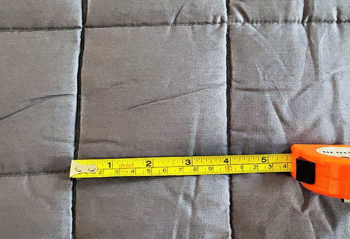 photo of the internal pockets of the cosi home weighted blanket, with a tape measure showing they are 10cm squares