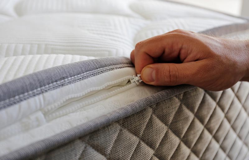 photo of a person's hand unzipping a mattress topper