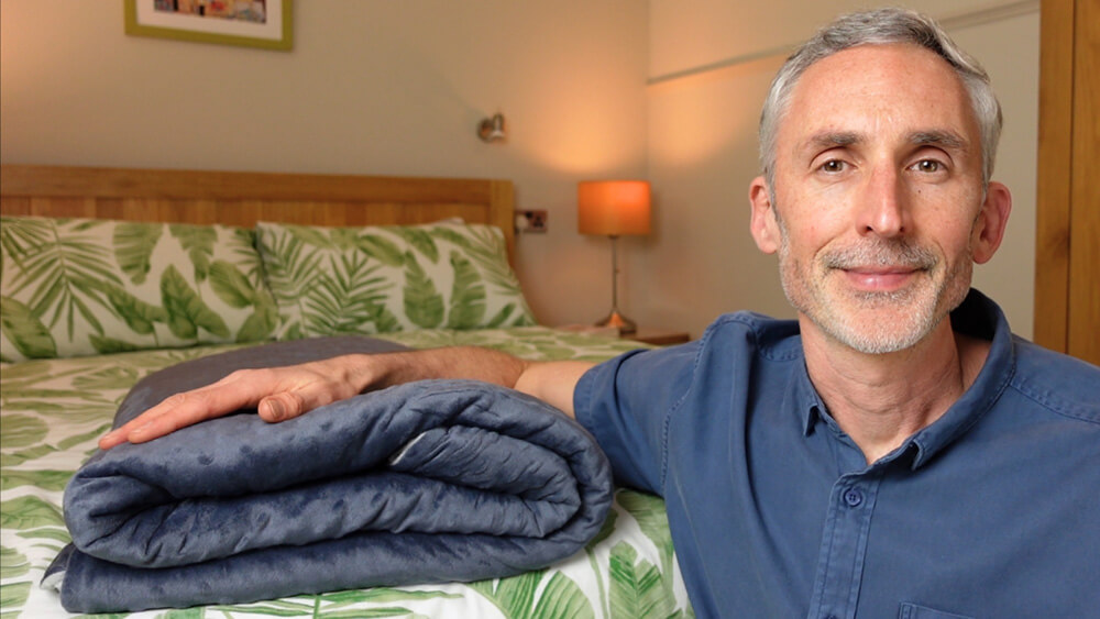 man with arm on top of a weighted blanket with its duvet cover 