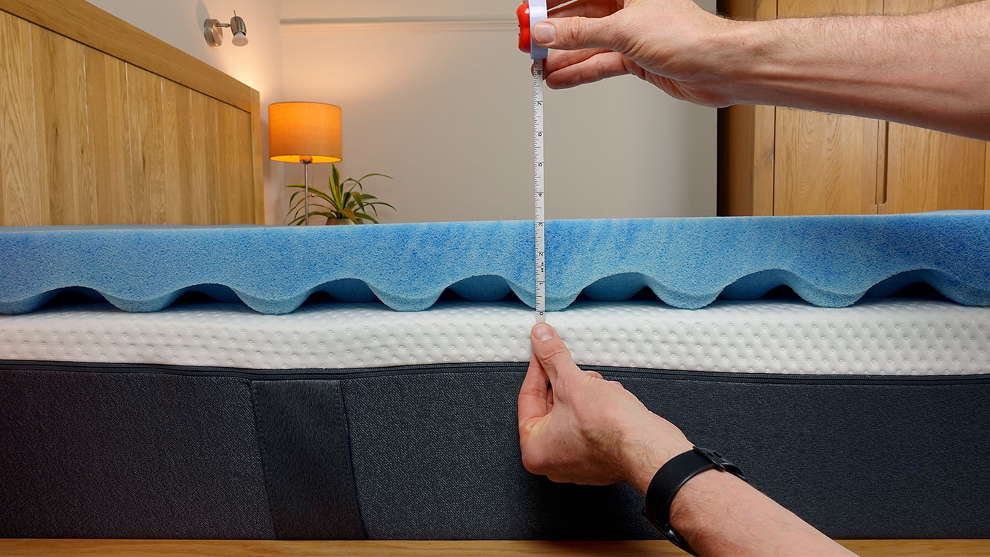 man measuring the thickness of the sleep innovations topper