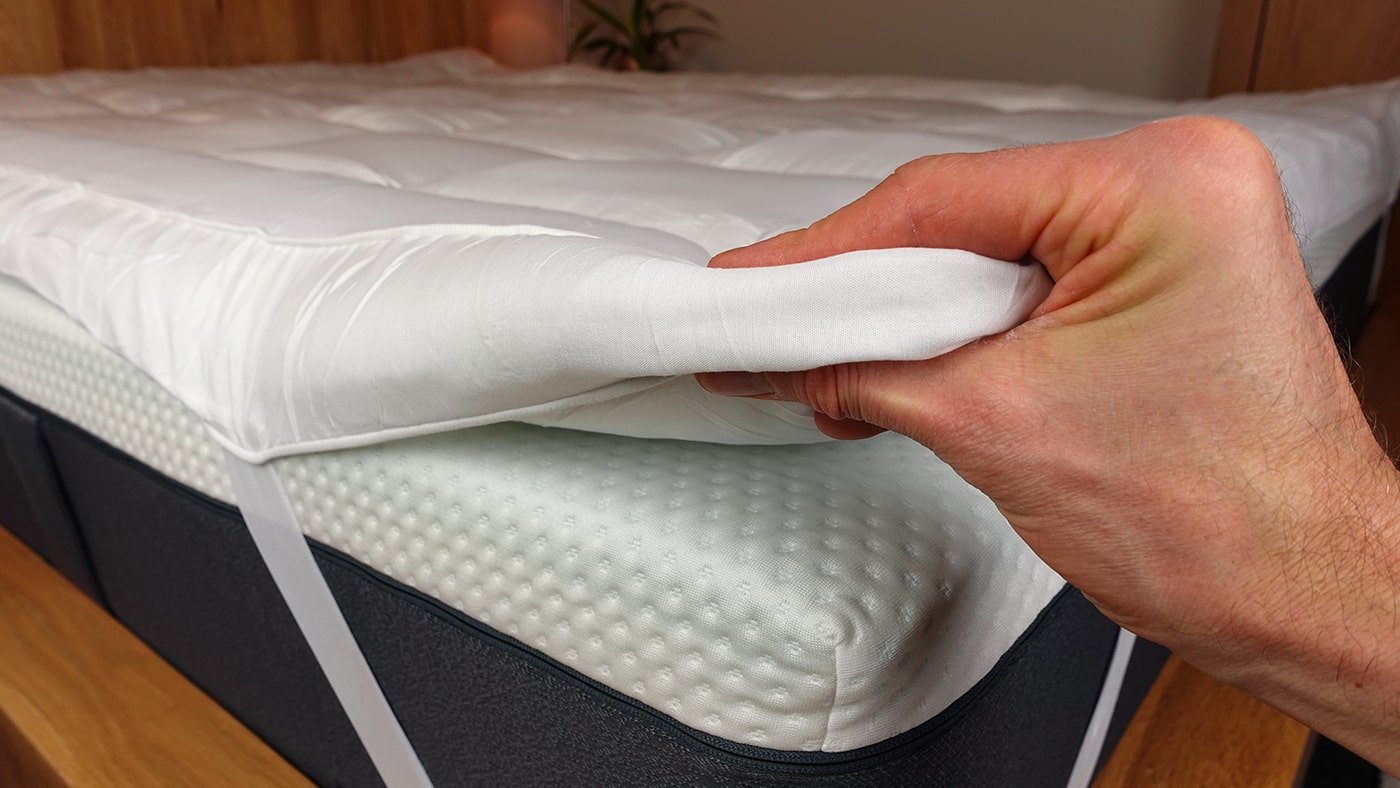 a man's hand compressing the MightySoft mattress topper