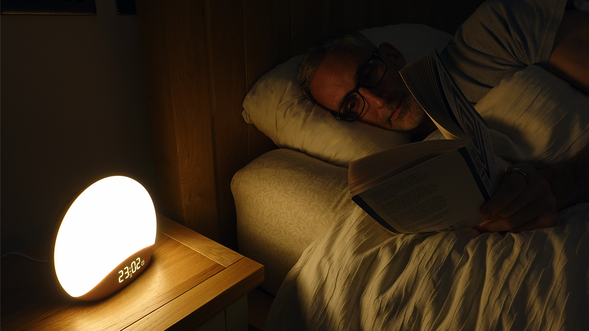 man reading with the bright light of the Reacher sunrise alarm clock