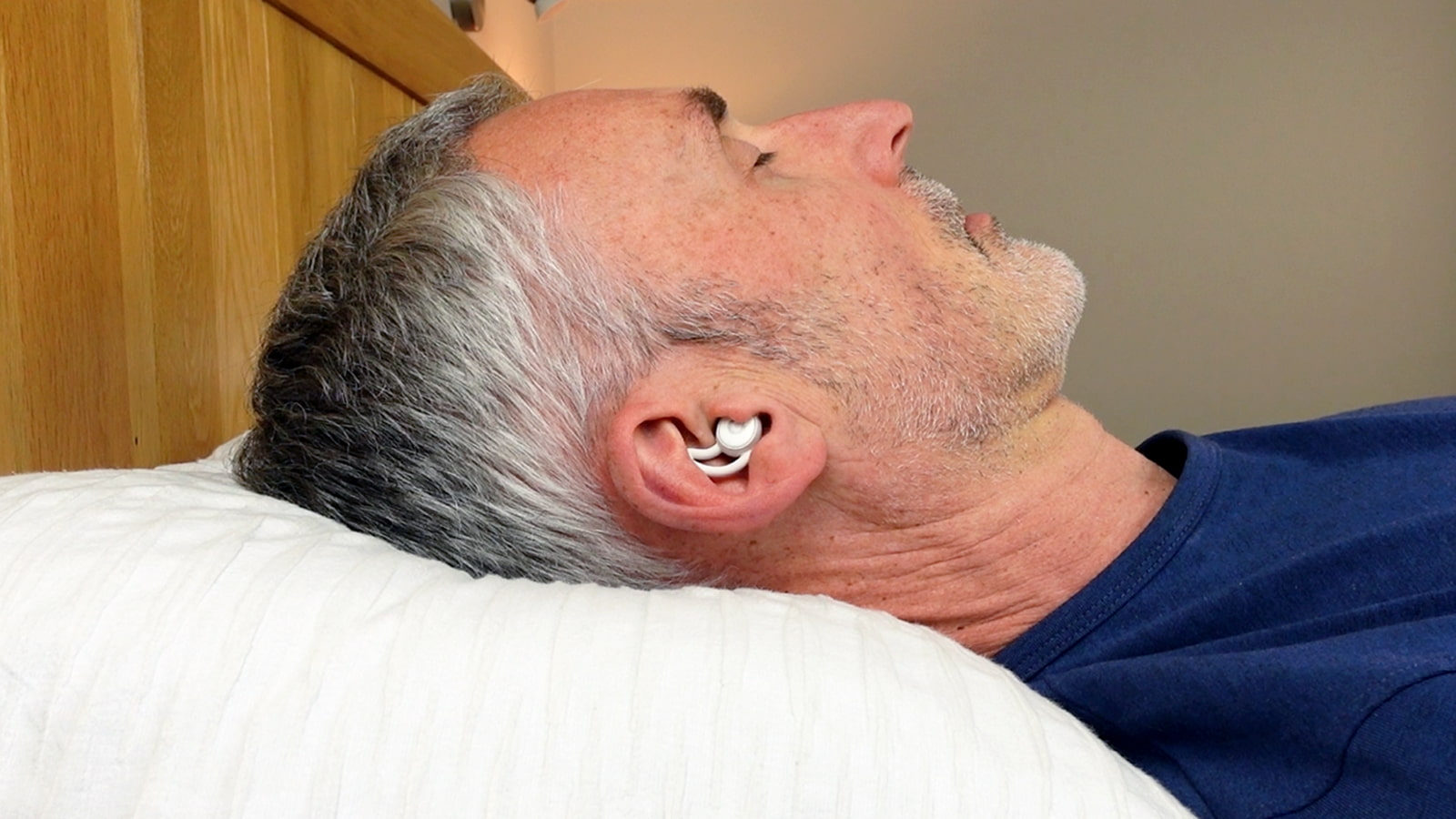 man wearing the Ozlo Sleepbuds in bed