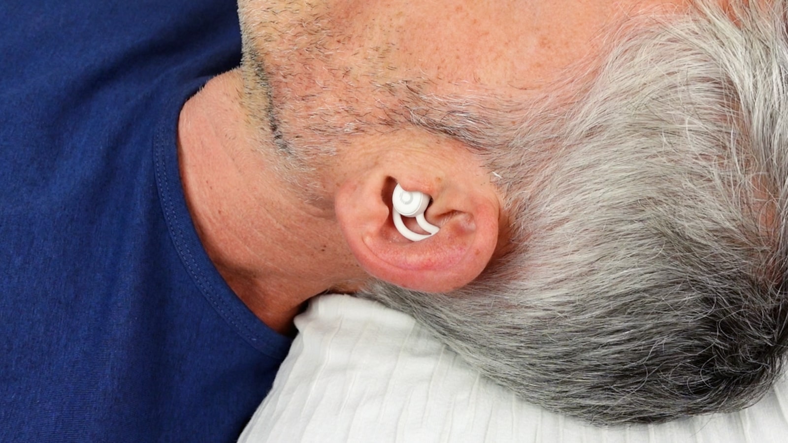 man lying in bed wearing the ozlo sleep buds