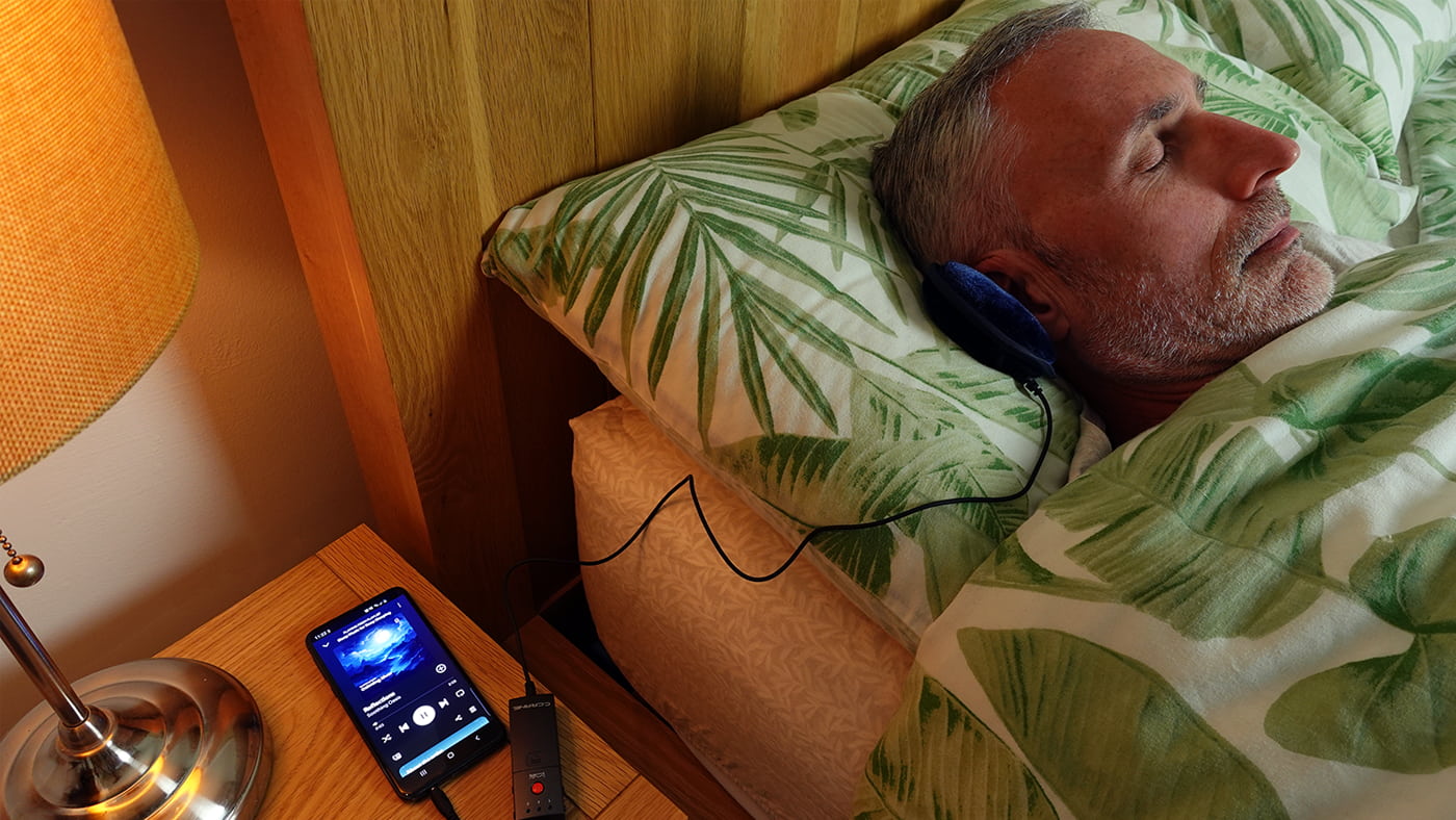 man using the C. Crane Soft Speaker 3k in bed