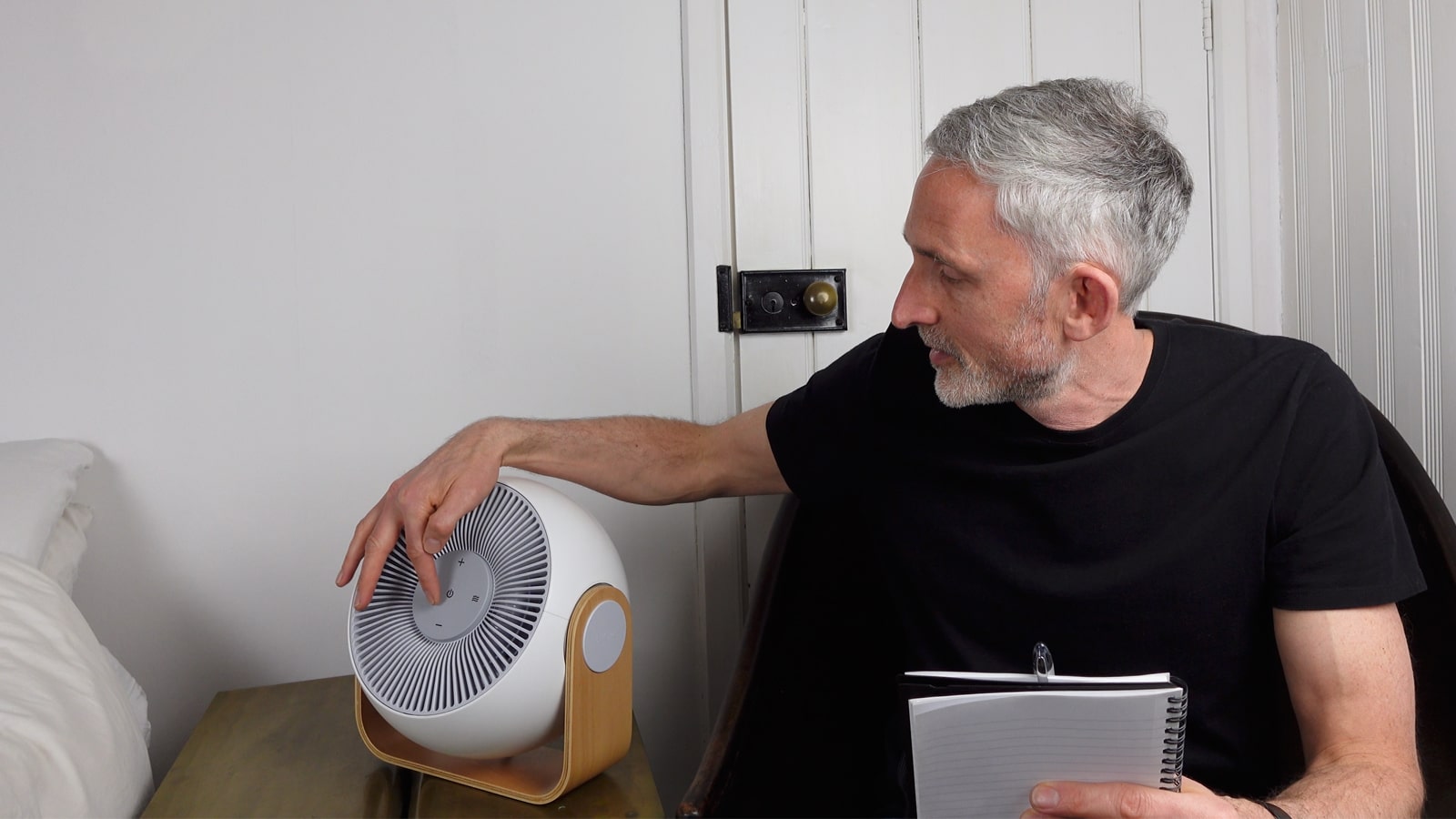 man testing white noise machine in old bedroom
