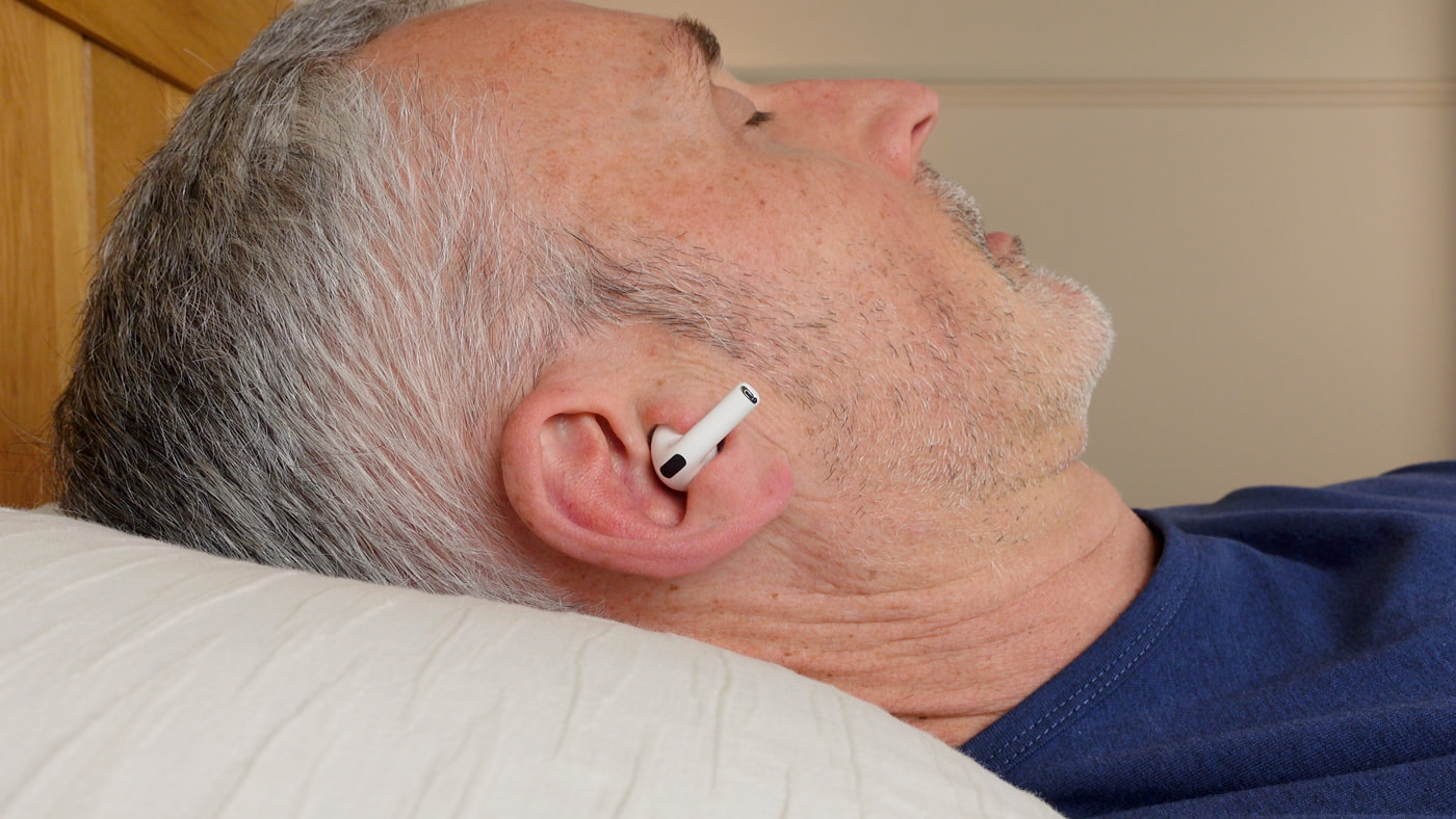 man wearing Apple AirPods Pro 3 in bed