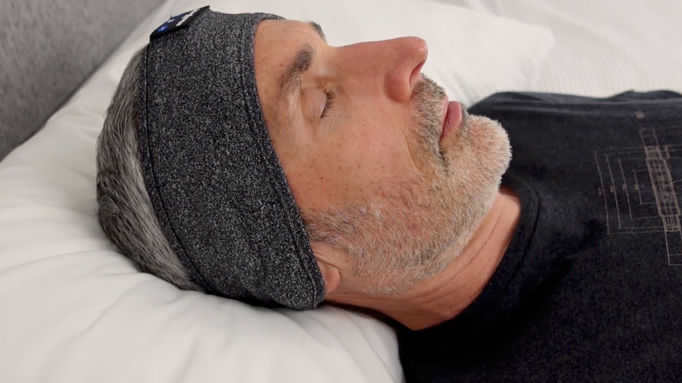 man wearing the Musicozy headphones in bed